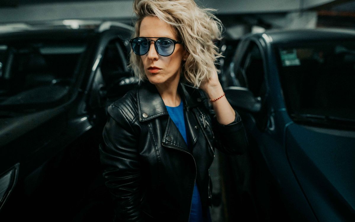 Elegancka kobieta w skórzanej kurtce, pozująca pewnie w miejskim otoczeniu