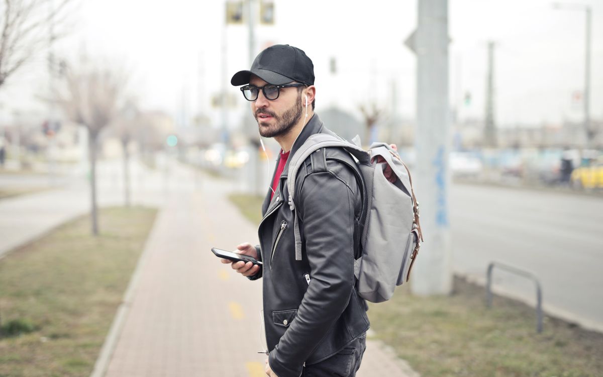 Modnie ubrany młody mężczyzna w Budapeszcie sprawdzający telefon na ruchliwej ulicy