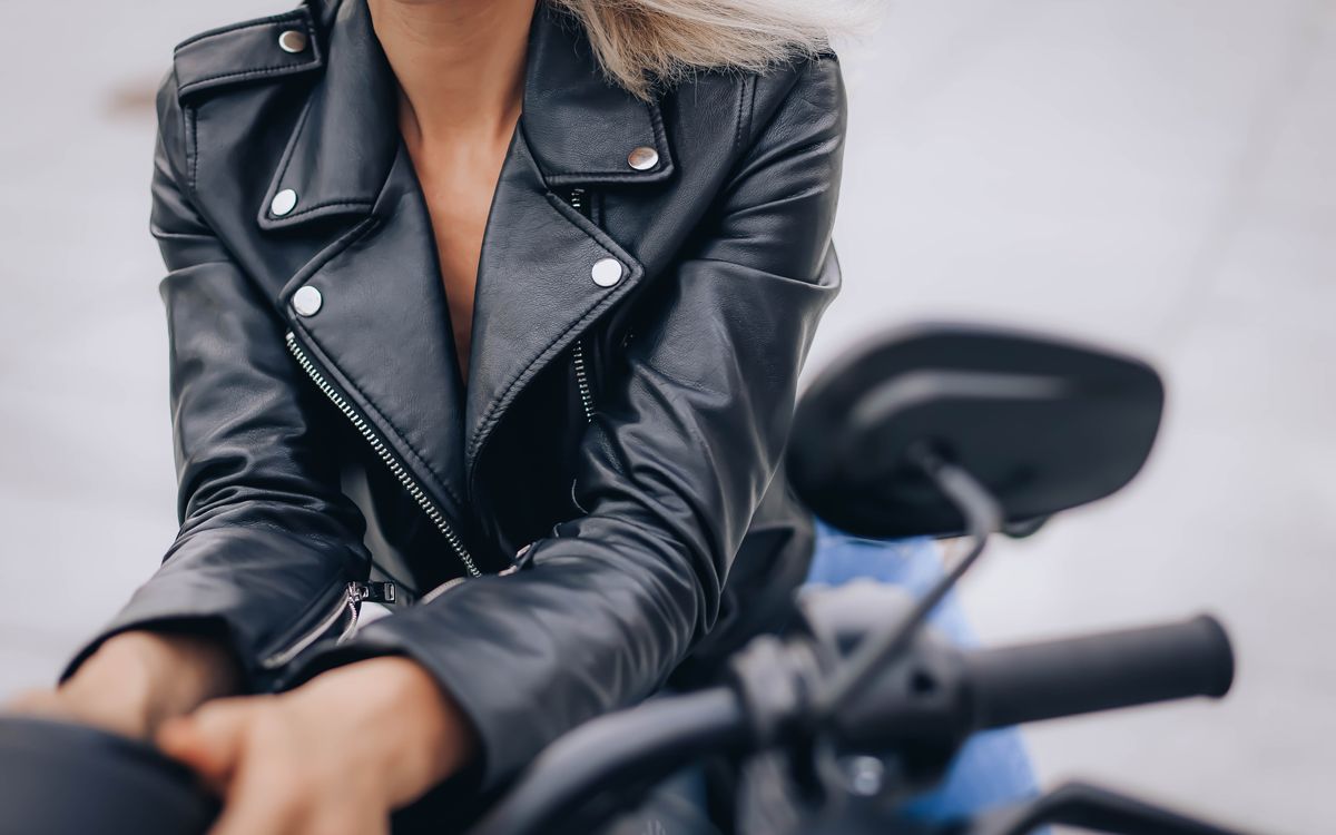 Zbliżenie kobiety w czarnej skórzanej kurtce ze stójką podczas jazdy motocyklem