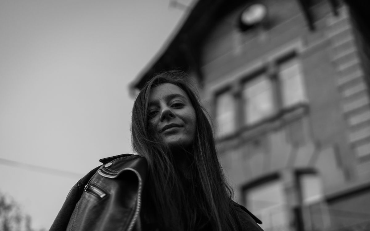 Uśmiechnięta kobieta w skórzanej kurtce na dworze, portret czarno-biały