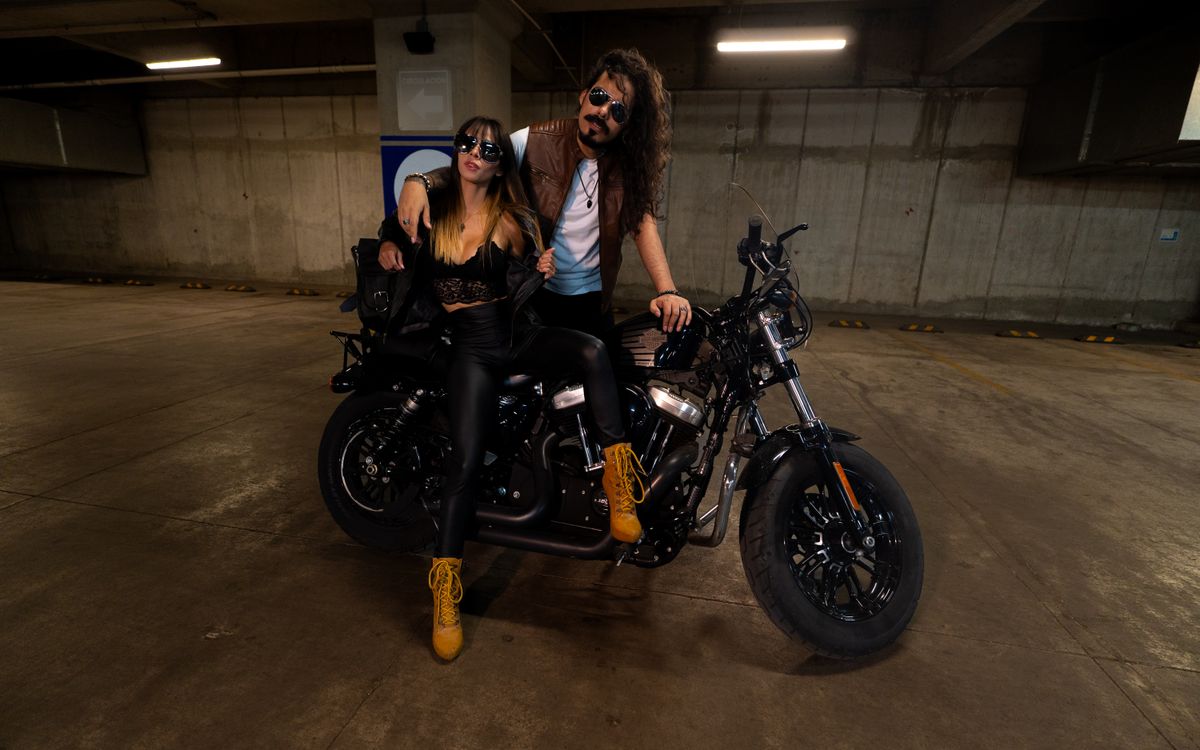 Elegancka para w skórzanych stylizacjach pozująca przy motocyklu w garażu
