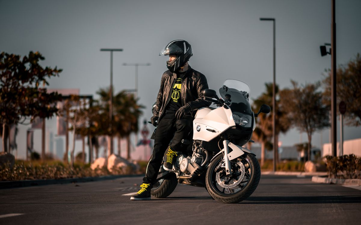 Motocyklista w czarnym stroju przy motocyklu w świetle dnia