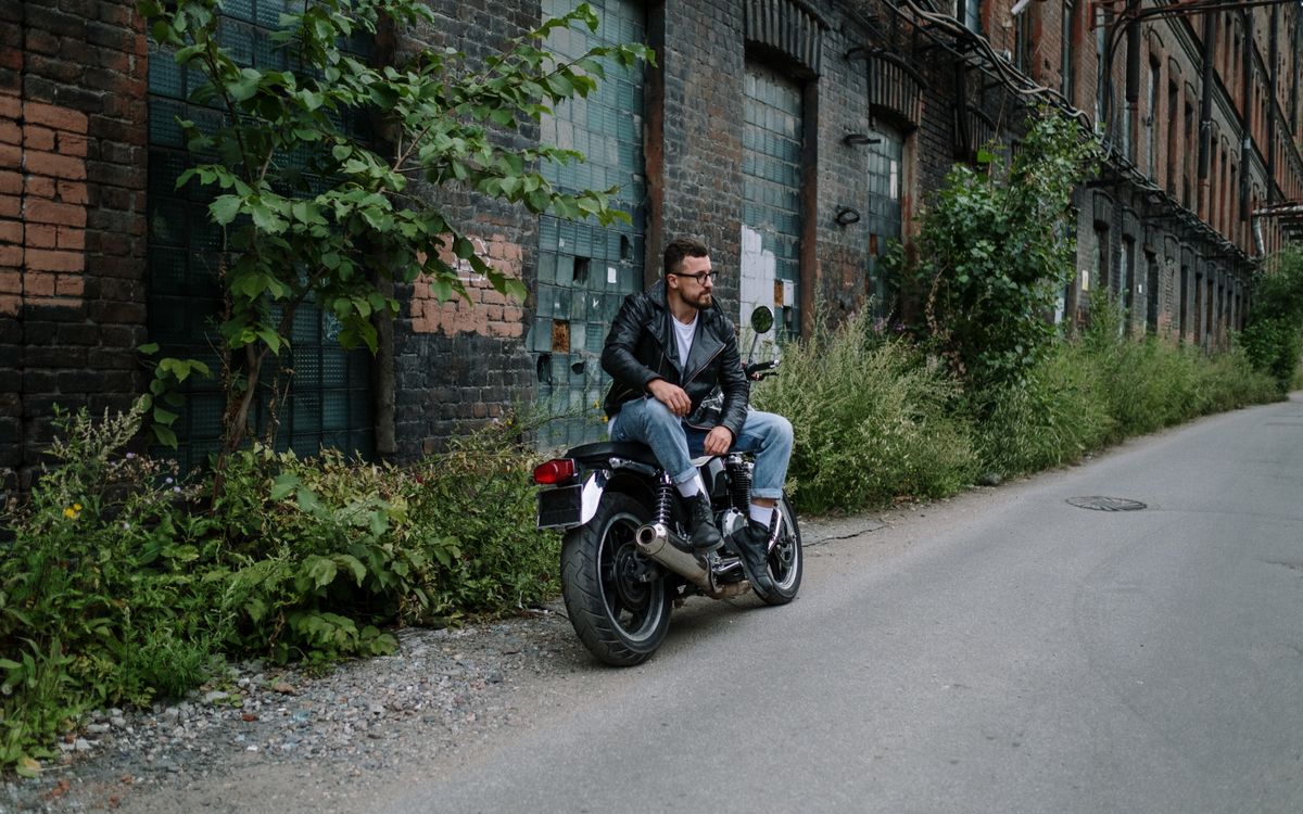 Mężczyzna w skórzanej kurtce siedzący na motocyklu w miejskiej scenerii