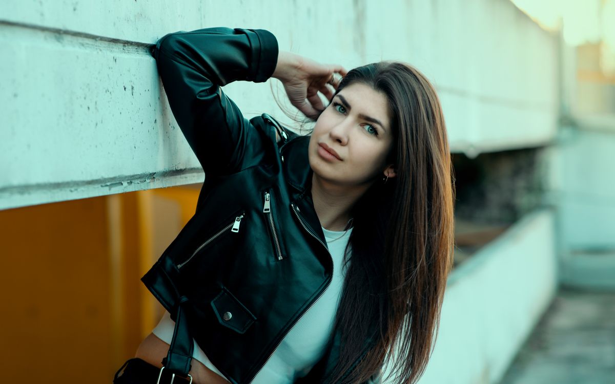 Stylowa kobieta w czarnej skórzanej kurtce pozuje pewnie w miejskiej scenerii
